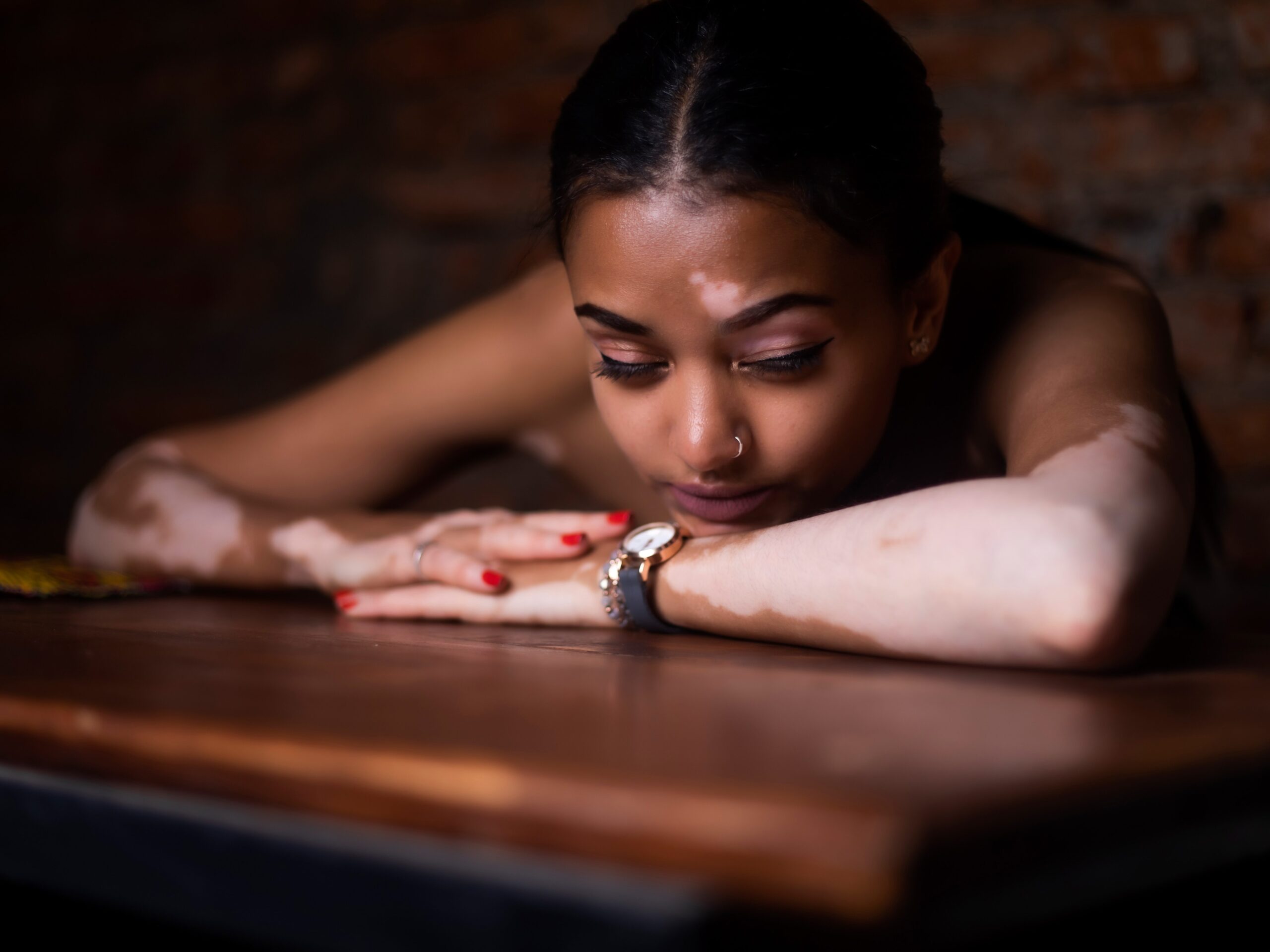 woman in red and white floral dress lying on brown wooden table